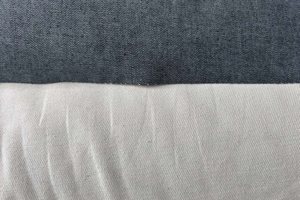 Mép một tấm denim gấp lại: nửa trên là mặt ngoài xanh chàm đậm, nửa dưới là mặt trong gần như trắng