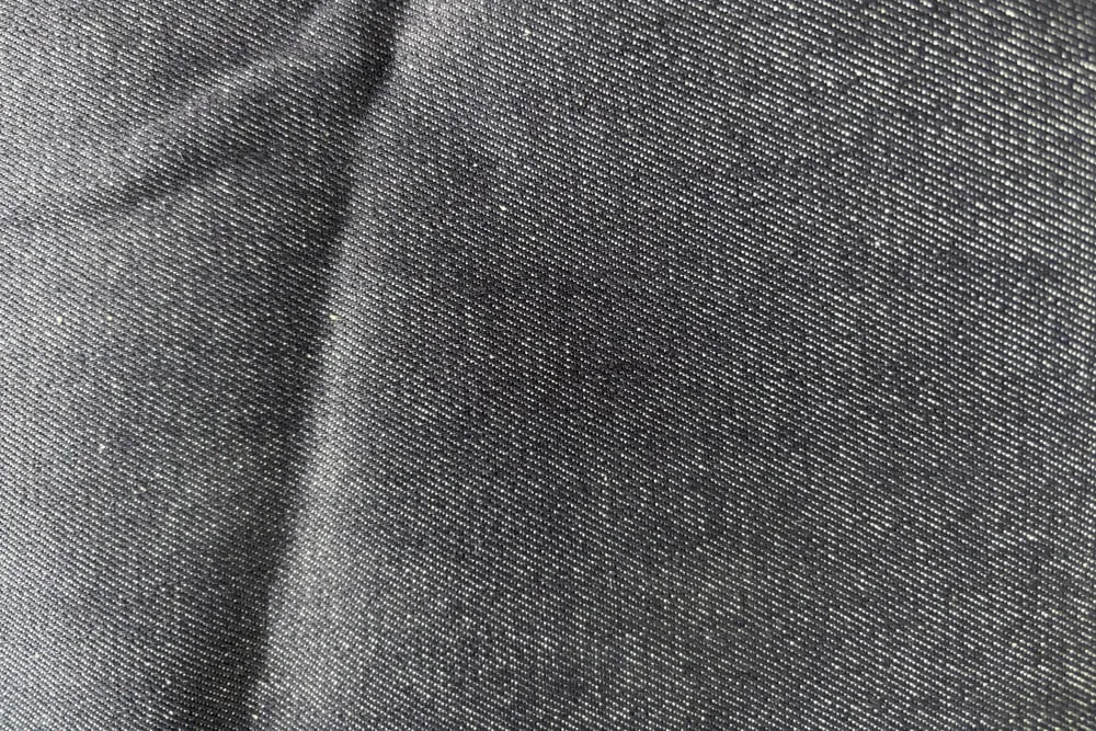 Cận cảnh mặt vải denim đen, thấy rõ những đường gân chéo chạy nghiêng đều nhau