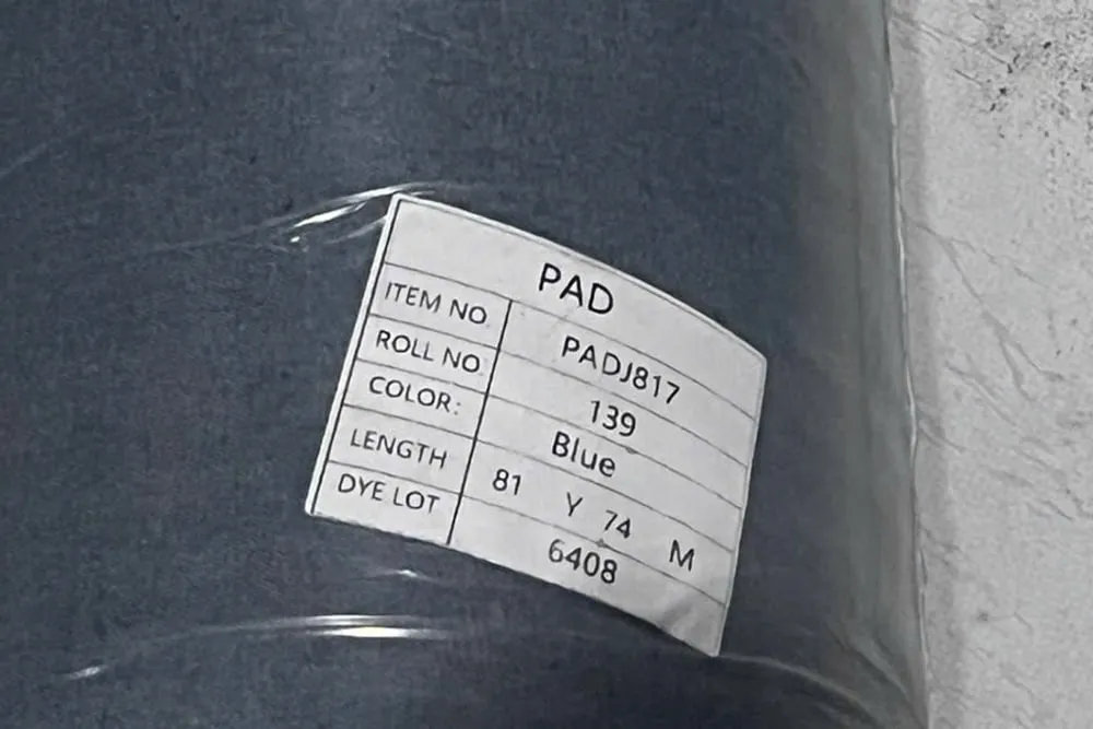Cận cảnh tem dán trên một cây vải jean bọc nilon, ghi mã hàng PADJ817, số cây 139, màu Blue, chiều dài 81 yard tương đương 74 mét, và dòng DYE LOT 6408
